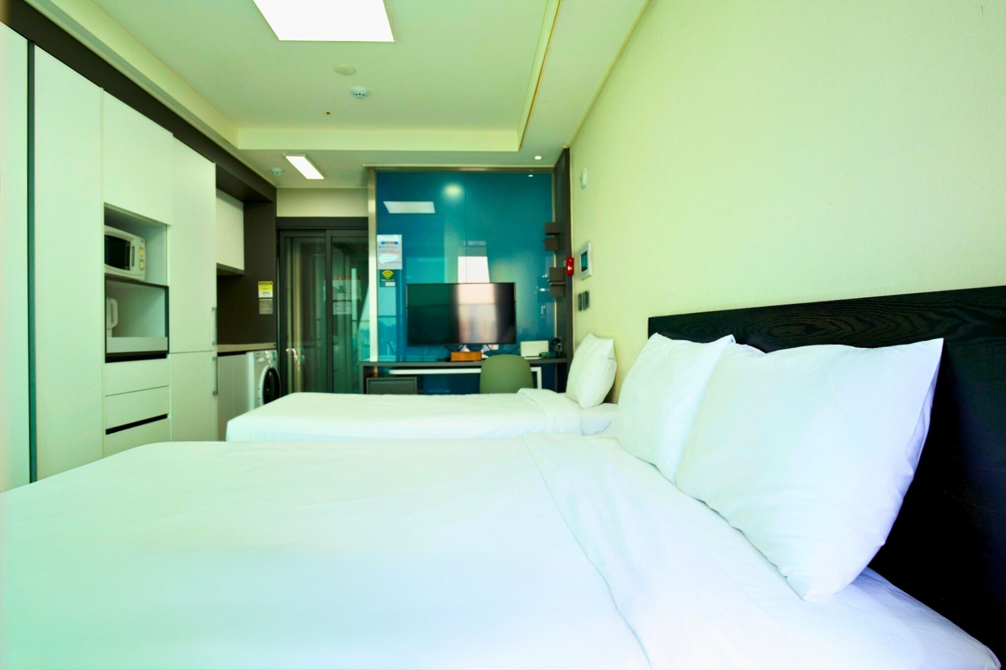 A hotel room with a bed, a desk, a TV, and a microwave.