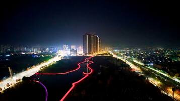 Paisaje urbano nocturno con edificios iluminados, un río y un puente.
