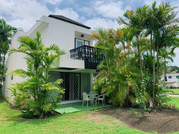 A modern two-story house with a balcony, surrounded by lush greenery and a well-maintained lawn. - Spring Bookings! ANIDELE ZEN -2BR on Golf Course. Near Beach w/ Pool, Golf, BBQ. (Rockley Golf and Country Club)