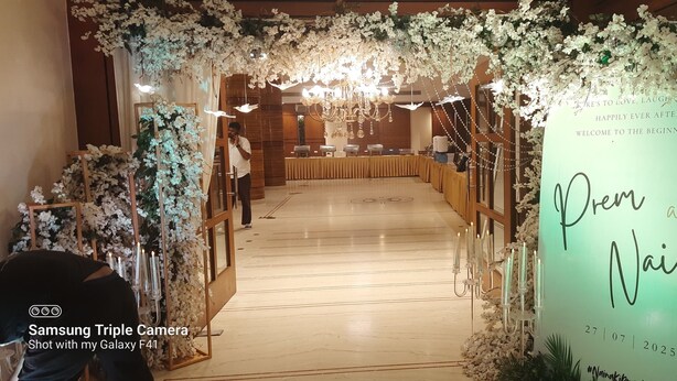A wedding reception venue with floral decorations, a reception table, and a sign welcoming guests. - Hotel MD's Continental (East Jorhat)