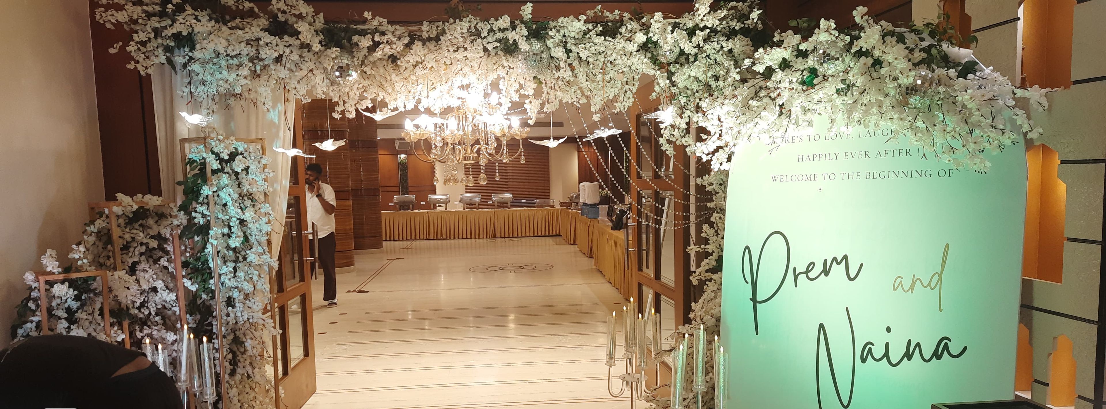 A wedding reception venue with floral decorations, a reception table, and a sign welcoming guests.
