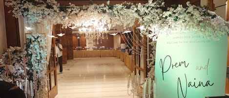 A wedding reception venue with floral decorations, a reception table, and a sign welcoming guests.