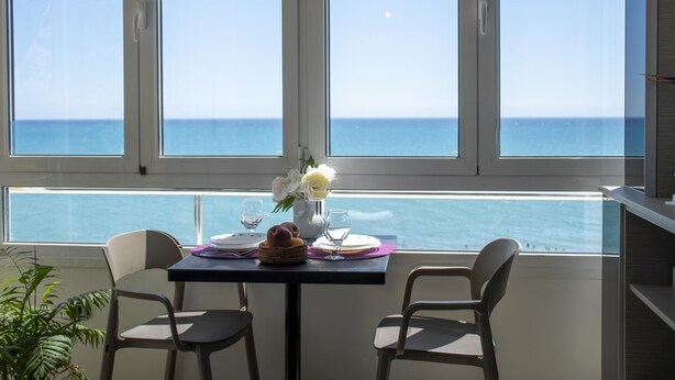 Een eetgedeelte met een gedekte tafel voor twee, met uitzicht op een heldere blauwe zee.