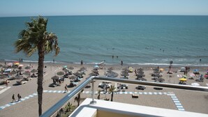 Een strand met parasols, ligstoelen en een palmboom.