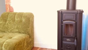 A room with a green sofa, a black wood-burning stove, and a marble floor. - W.1. Ruhiges Apartment mit Veranda am Schlossgarten (Hirschhorn (Neckar))