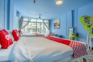 Ett hotellrum med två sängar, ett stort fönster, utsikt över byggnader och en tavla på väggen.