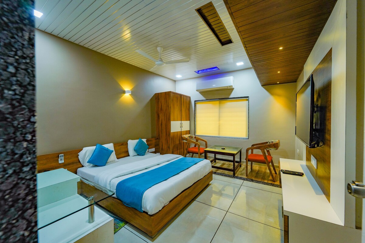 A hotel room with a bed, a desk, a chair, a TV, and a wardrobe.
