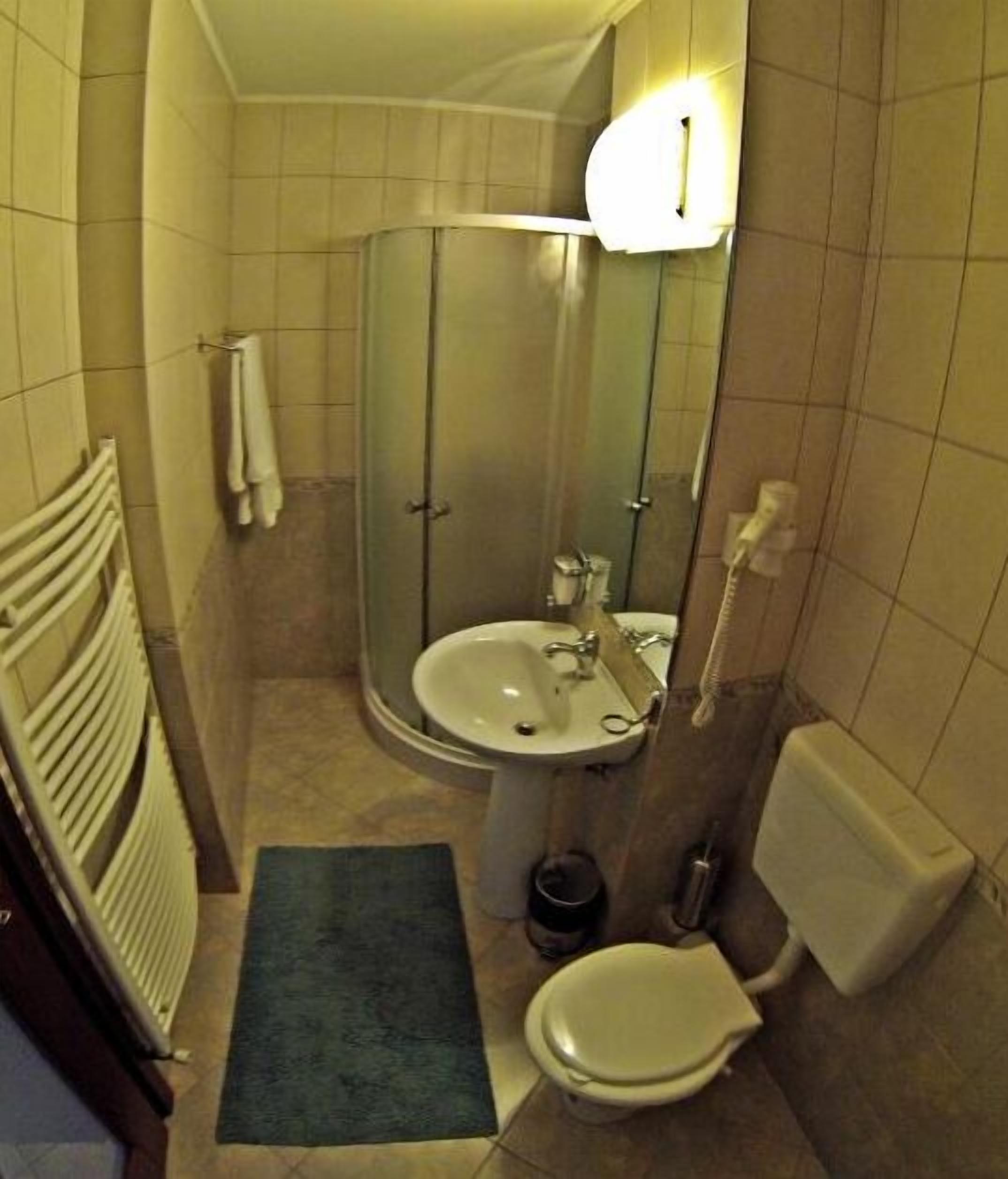 Un baño pequeño con ducha de vidrio, lavamanos, inodoro y perchero para toallas.