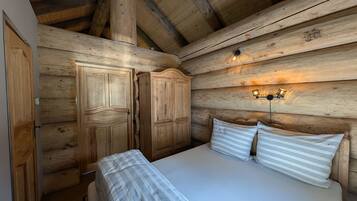 Ein Zimmer in einer Holzhütte mit einem Bett, zwei Kleiderschränken und einer Wandleuchte.