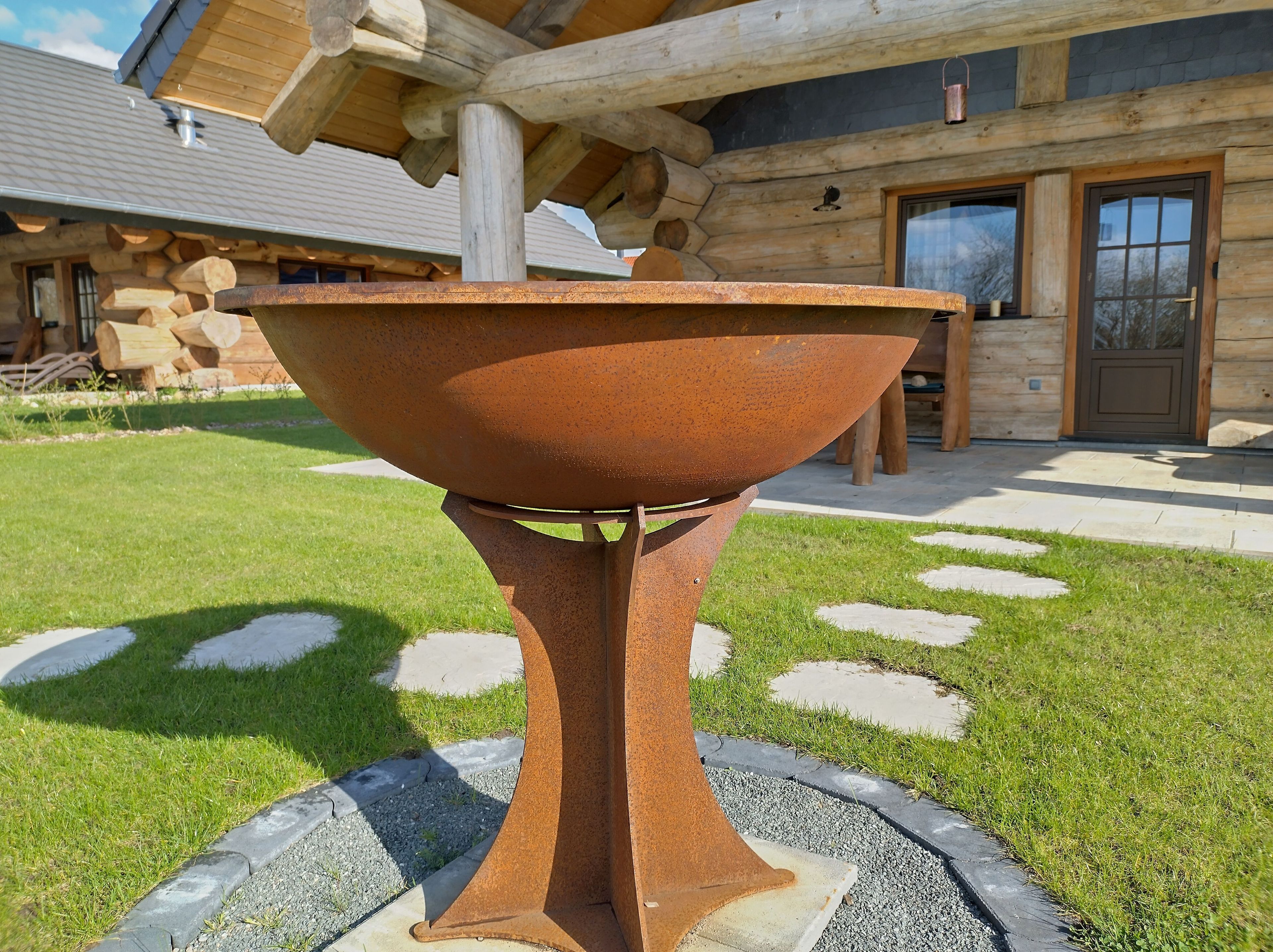 A rustic outdoor fire pit in front of a log cabin-style building.