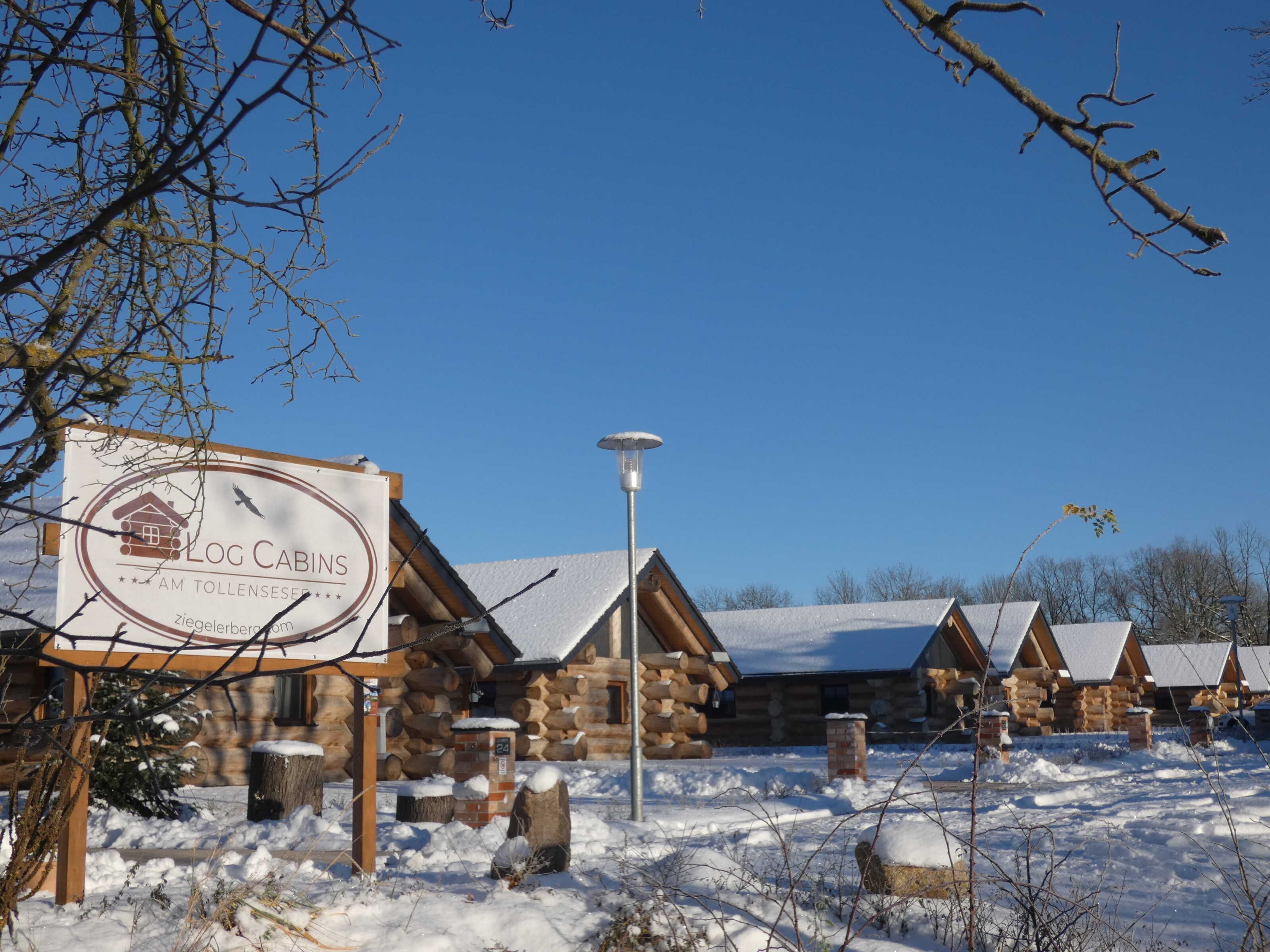 Ein Hotel in Form einer Blockhütte mit einem Schild, Holzbalken und verschneitem Boden.