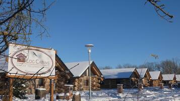 Ein Hotel in Form einer Blockhütte mit einem Schild, Holzbalken und verschneitem Boden.