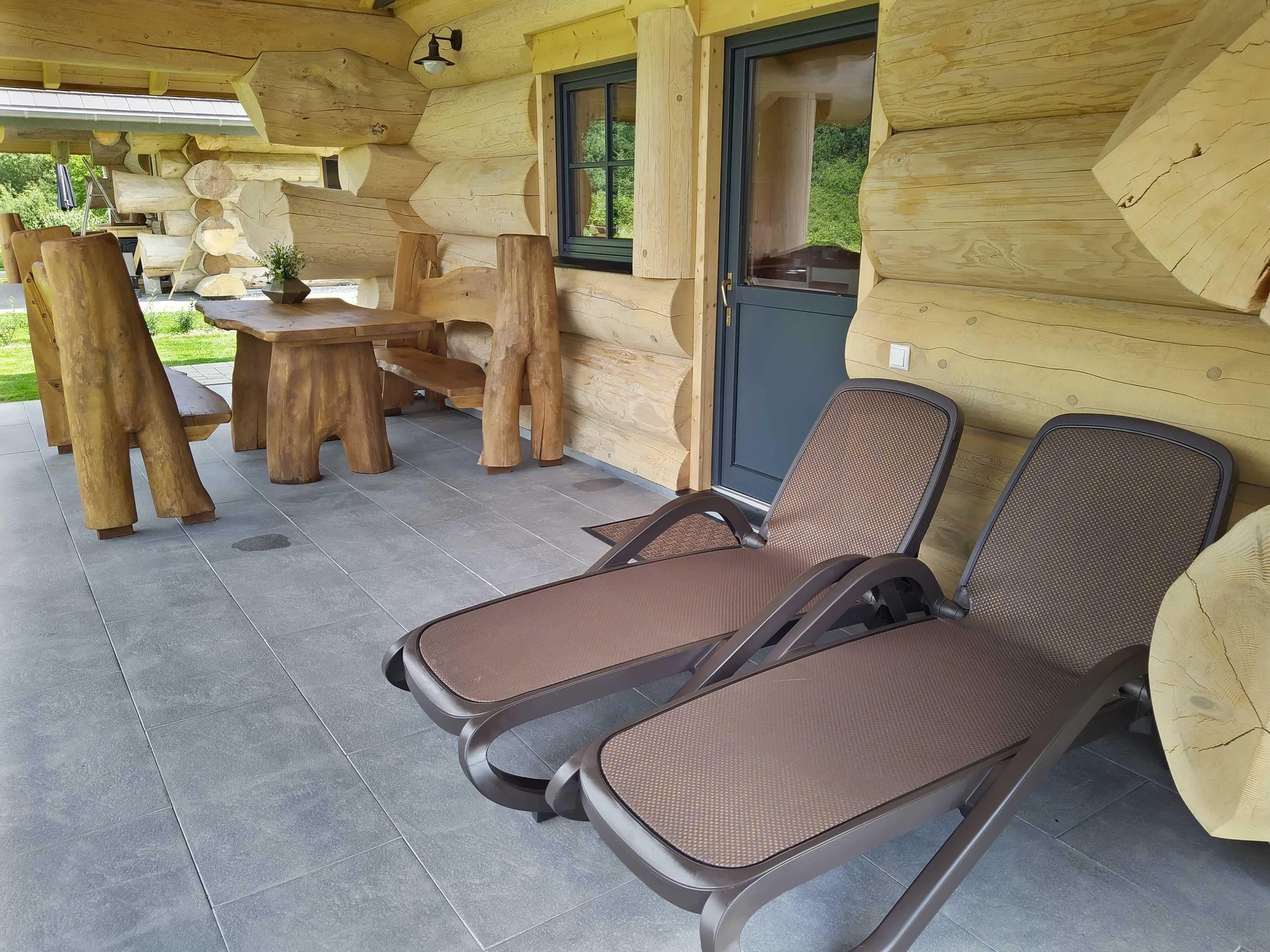 Eine Blockhütte mit einer Terrasse, ausgestattet mit zwei Metallstühlen und einem Holztisch.