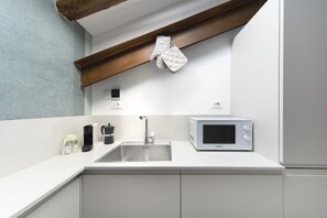 A modern kitchen with a white countertop, stainless steel sink, and a microwave.