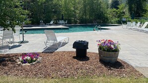 Un espace piscine comprenant des chaises longues, une petite piscine et un parterre de fleurs.