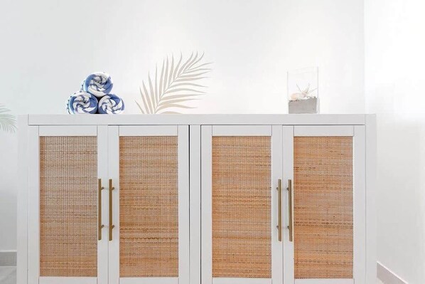 A white cabinet with four doors, each featuring a woven texture and gold handles.