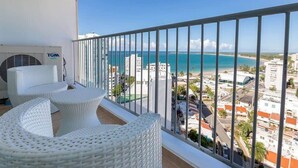 A balcony with white wicker furniture and a view of the ocean and buildings. - La Costal | Beachfront Studio Apt w/ Ocean View (Carolina)