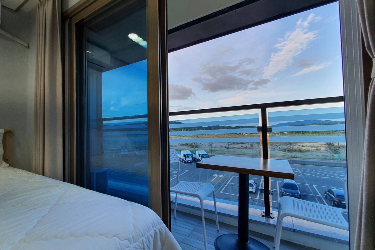 Une chambre d’hôtel avec une grande fenêtre, un lit et une petite table avec des chaises.