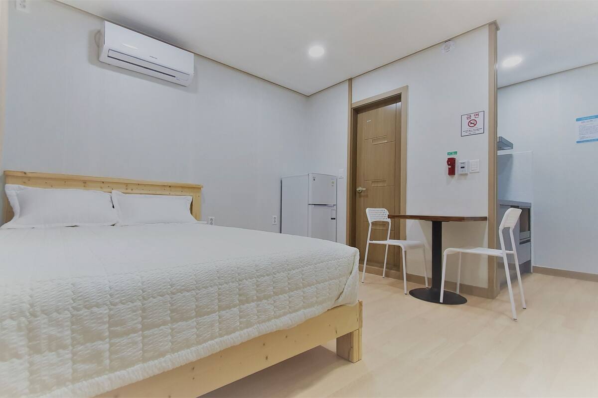 Une chambre à coucher comprenant un lit, un bureau, une chaise, une armoire et un tableau blanc.