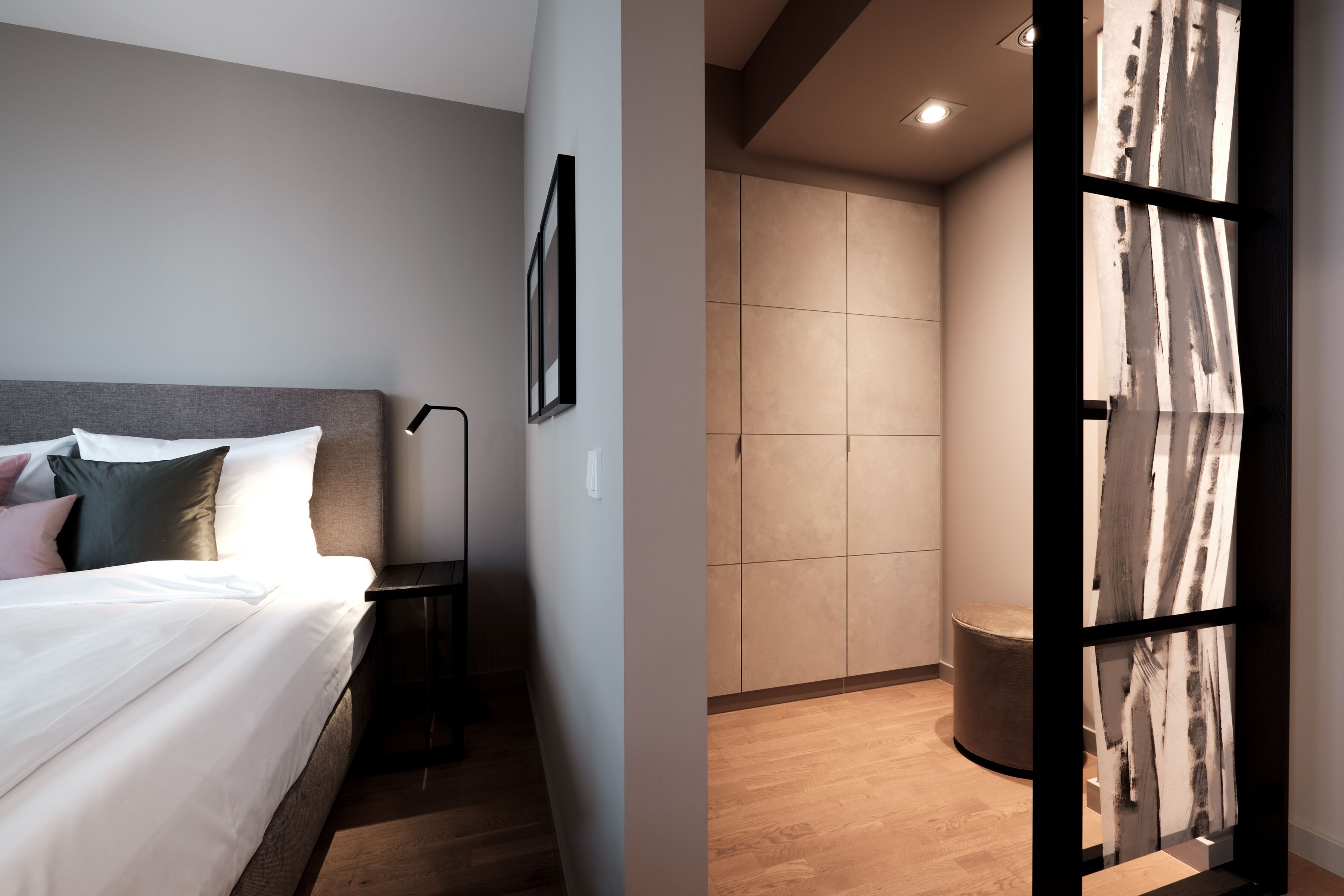 Una habitación de hotel moderna con una cama bien hecha, una mesita de noche y un cuadro colgado en la pared.