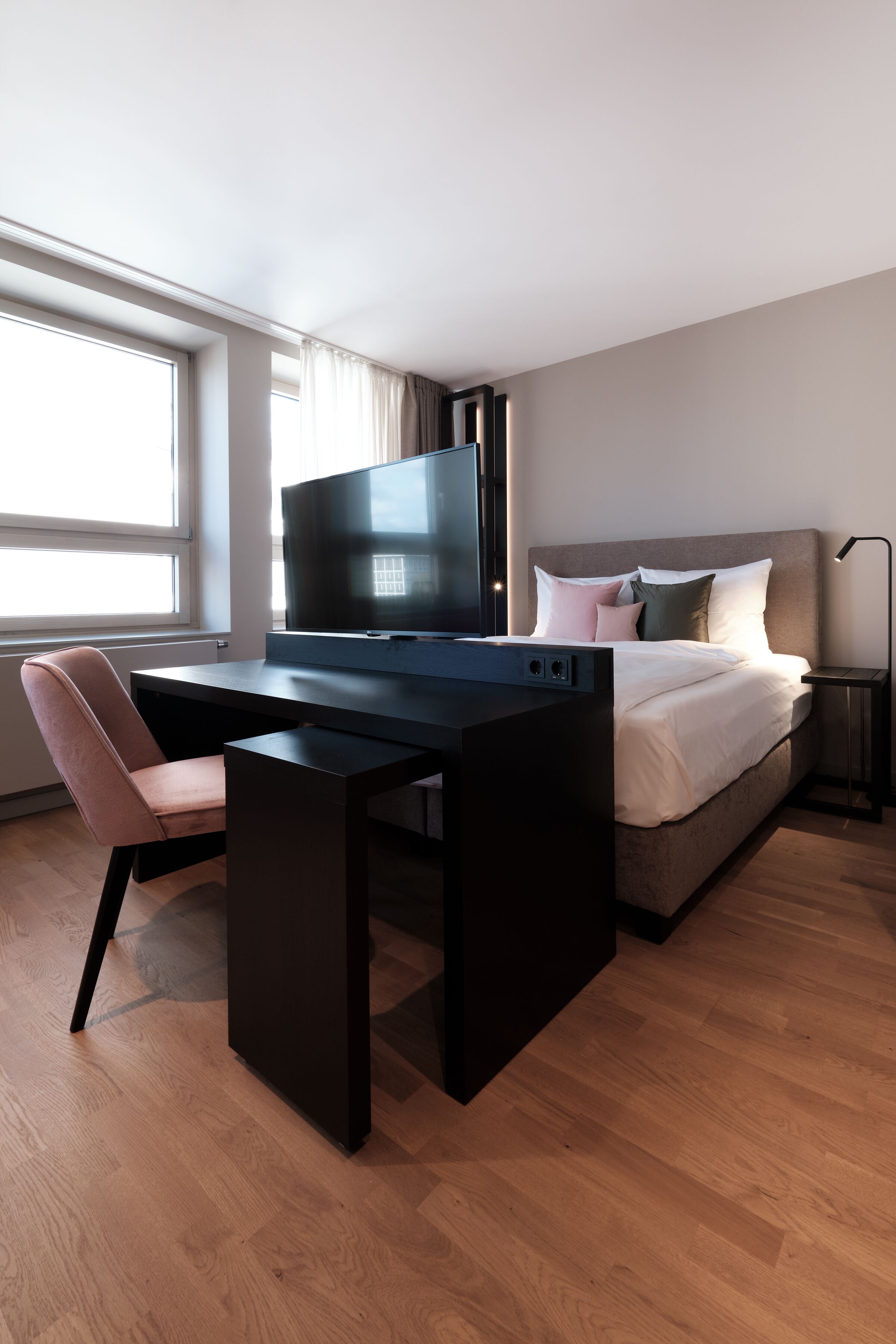 Een moderne hotelkamer met een bureau, stoel, bed en televisie.