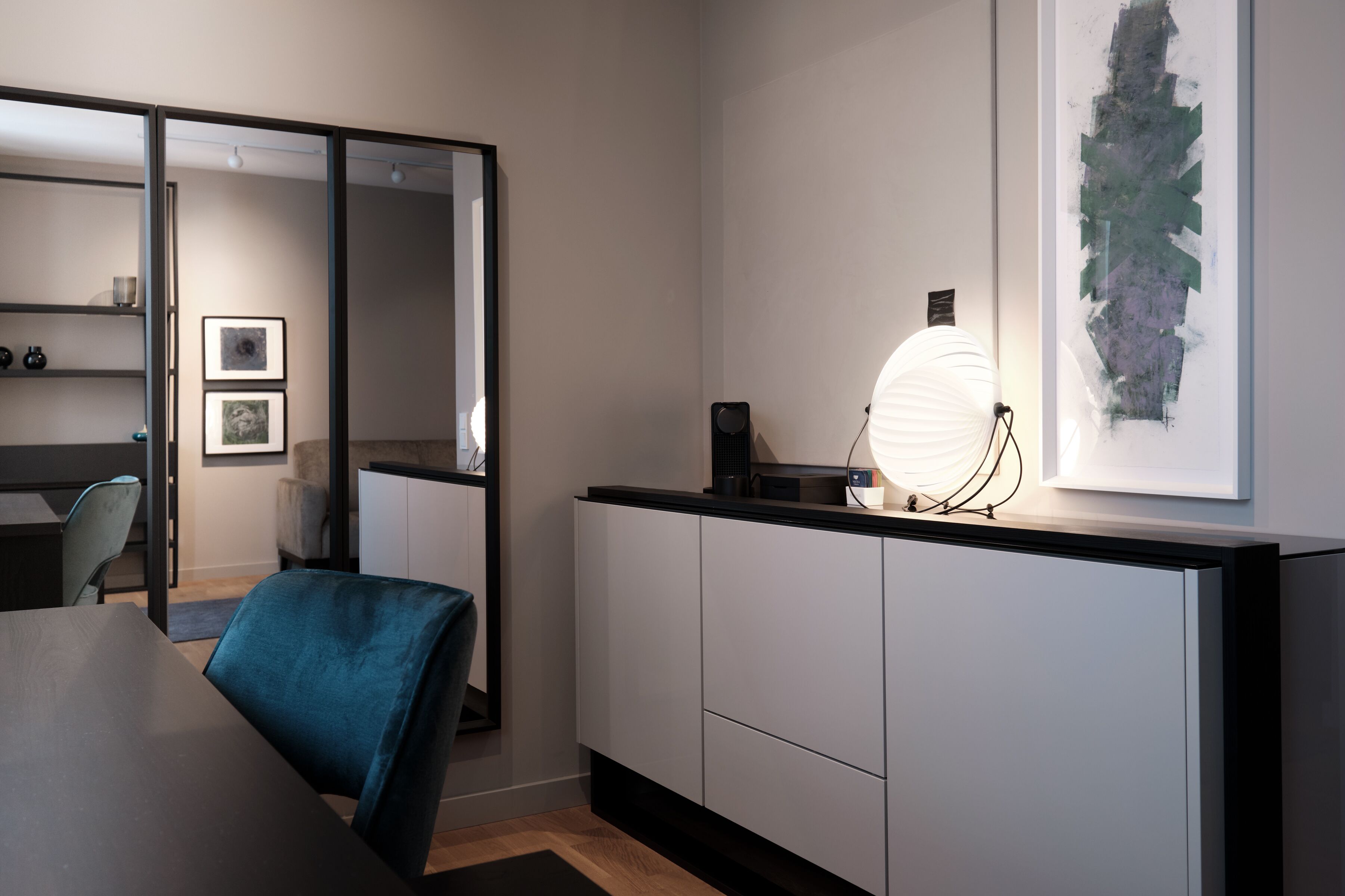 Un espacio de oficina moderno con un escritorio, una silla y un cuadro abstracto grande en la pared.