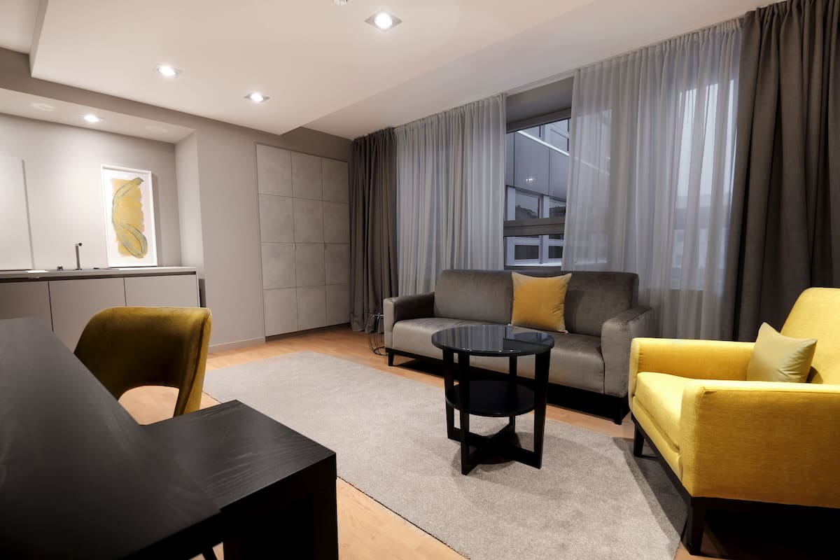 Un salon moderne comprenant un canapé, des fauteuils, une table basse et un coin repas avec une table et des chaises.