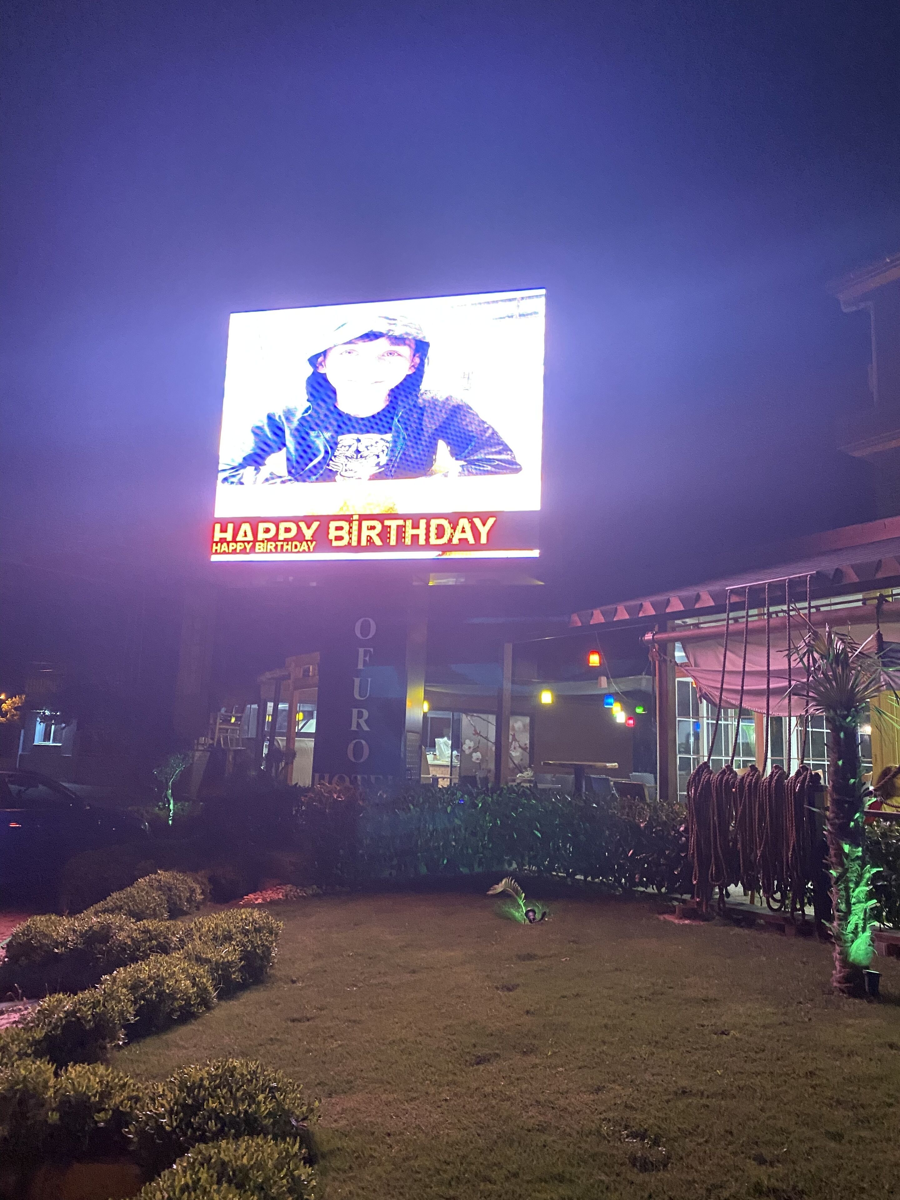 A building with a large illuminated sign displaying a birthday message.