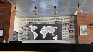A reception area with a world map display, framed pictures, and a brick wall. - Ofuro World Hotel Spa (Izmir)