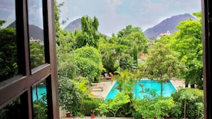 Una piscina rodeada de exuberante vegetación y montañas al fondo.