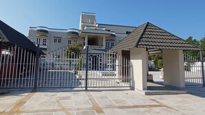 Una entrada protegida con un área pavimentada que conduce a un edificio con varios balcones y una entrada principal.