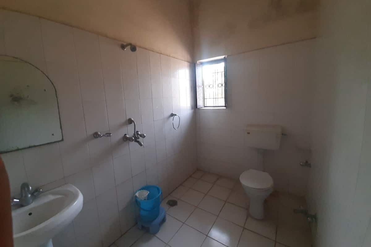 A small, basic bathroom with a sink, toilet, and window.