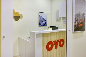 A reception desk with a wooden panel and the logo "OYO". - OYO 90090 Roselyn Inn 2 (Pasir Gudang)
