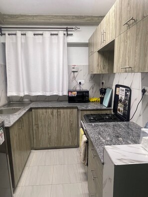 Una cocina con encimera de granito, estufa, microondas y armarios de madera.