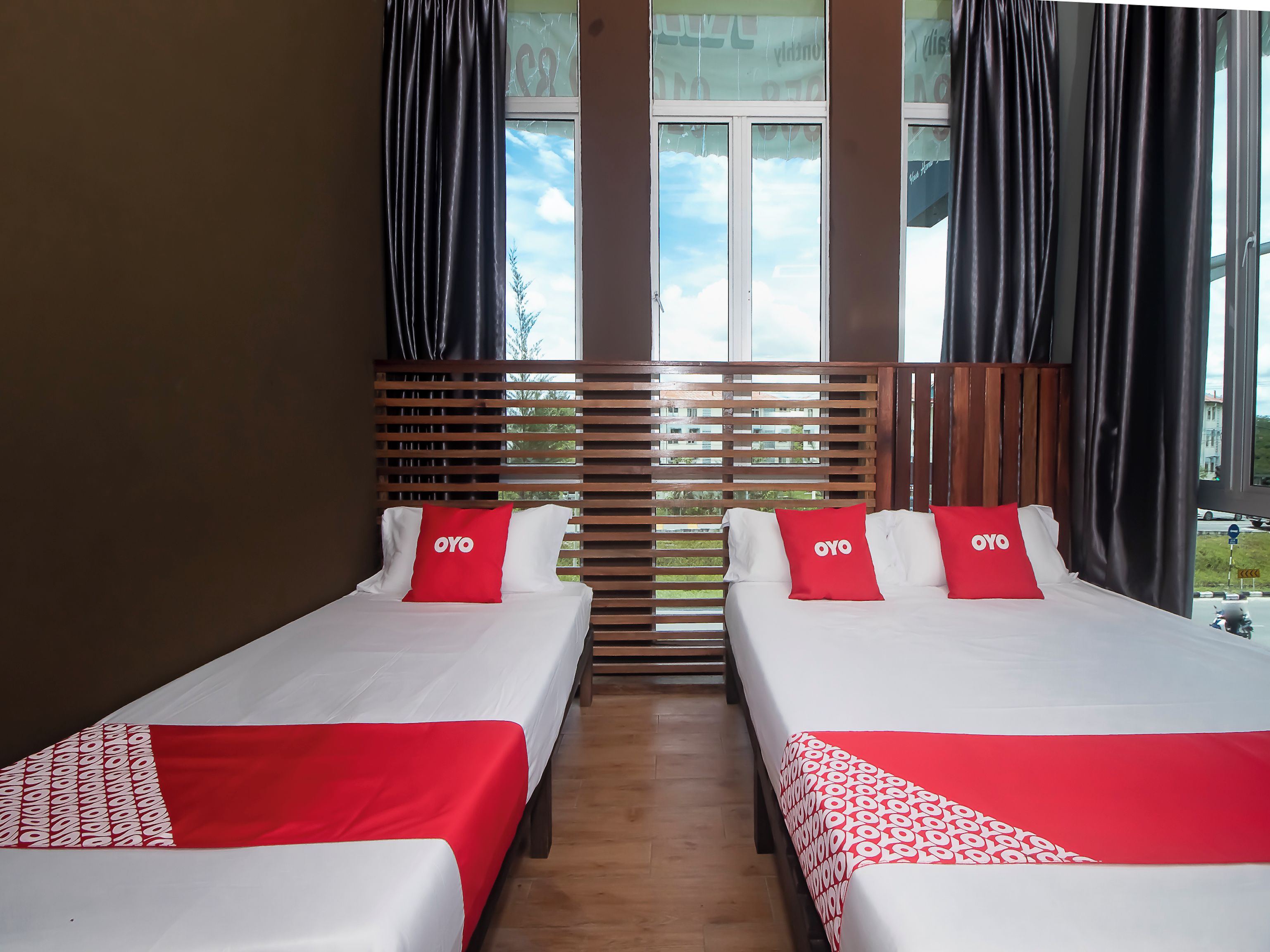 A hotel room with two beds, each with a red and white bedspread, and a wooden headboard.