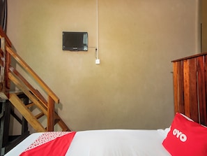 A room with a bed, a wooden staircase, a wall-mounted television, and a power outlet. - OYO 90094 Hi Inn 3 (Sibu)