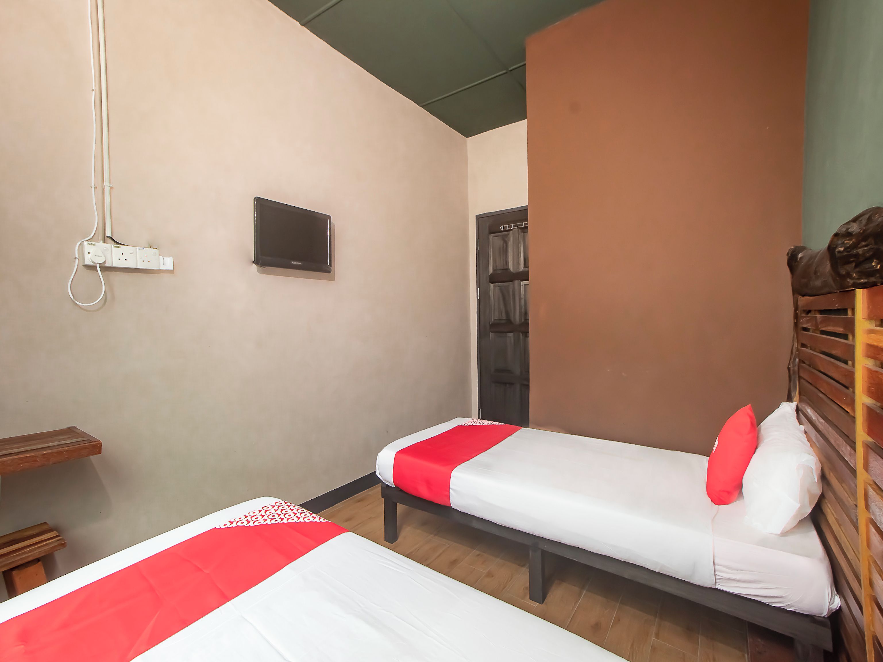 A hotel room with two beds, a TV, and a power outlet on the wall.