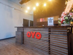 A reception desk with a wooden slat design, a prominent red logo, and a QR code for digital check-in.