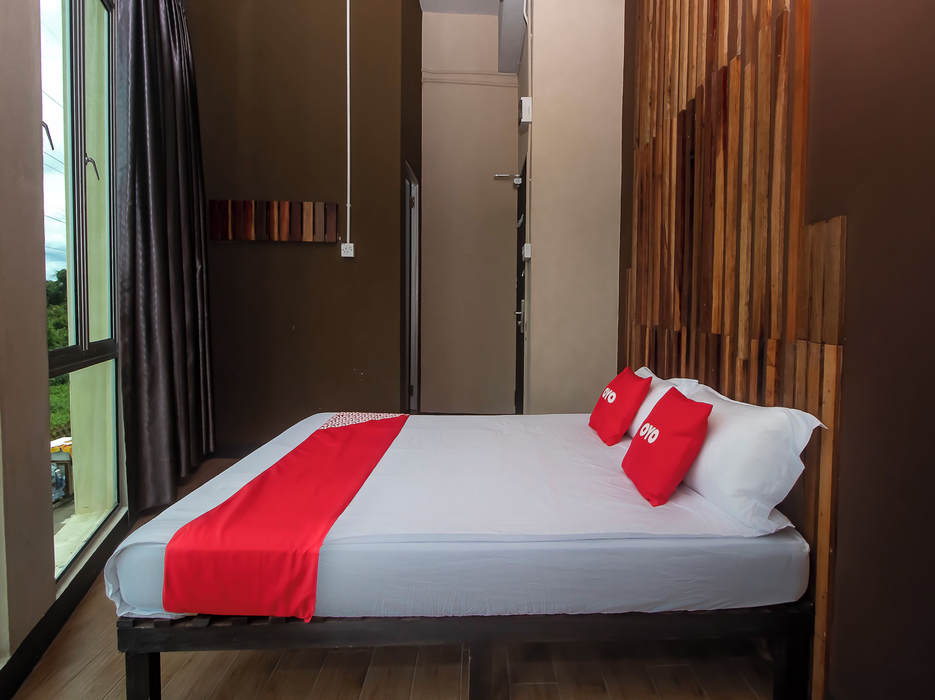 Una habitación de hotel con una cama, un ventanal y una pared revestida de madera.