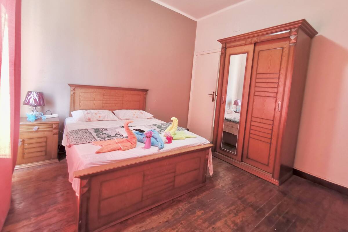 Une chambre à coucher avec un lit en bois, une armoire et une table de chevet avec une lampe.