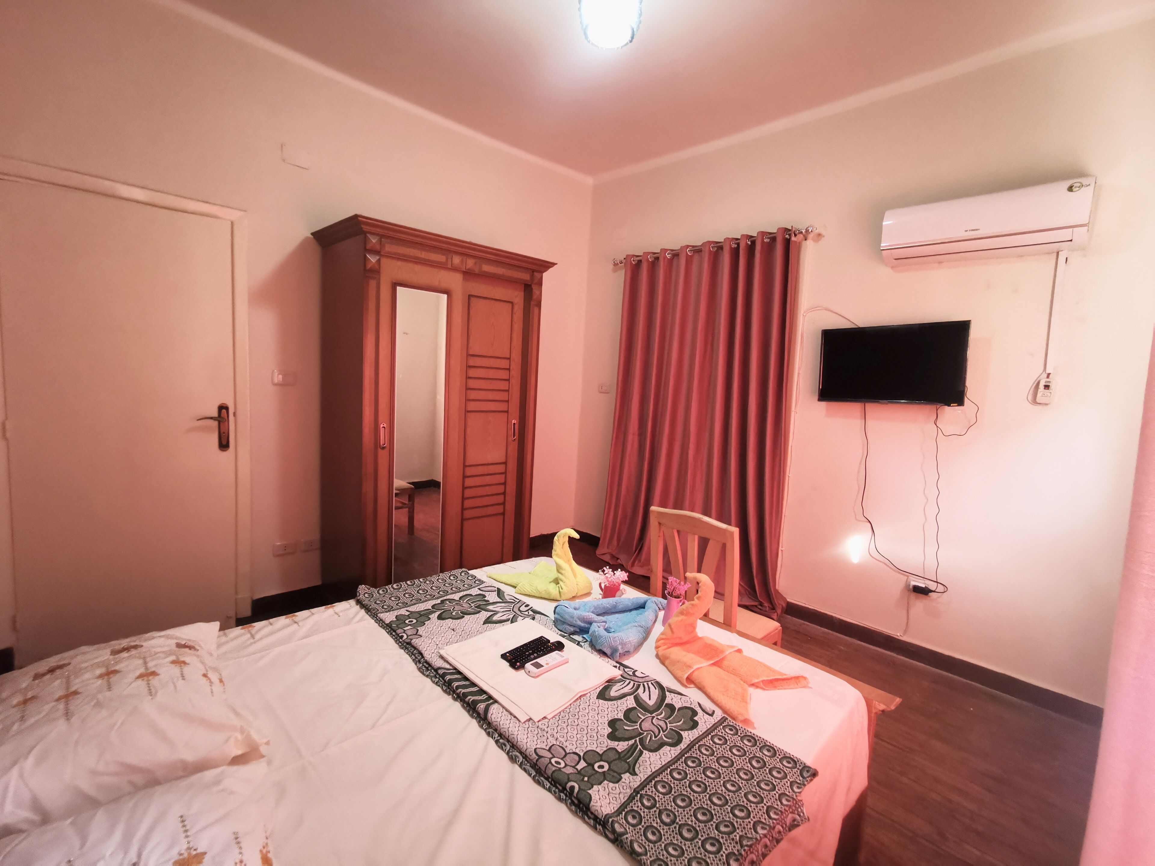 Ein Schlafzimmer mit Bett, Kleiderschrank, Fernseher und Klimaanlage.