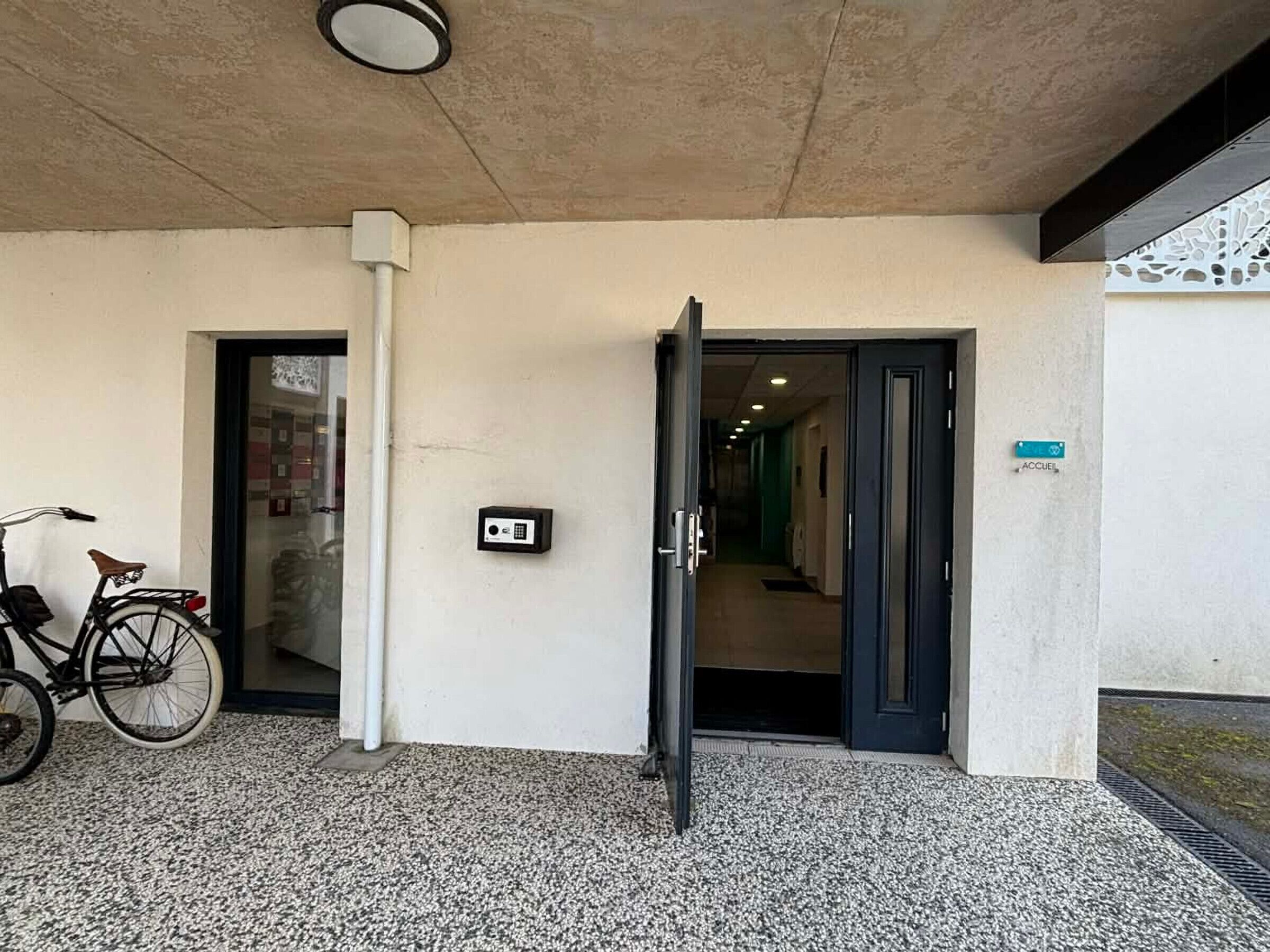 An entrance with a bicycle, a door, and a wall-mounted intercom.