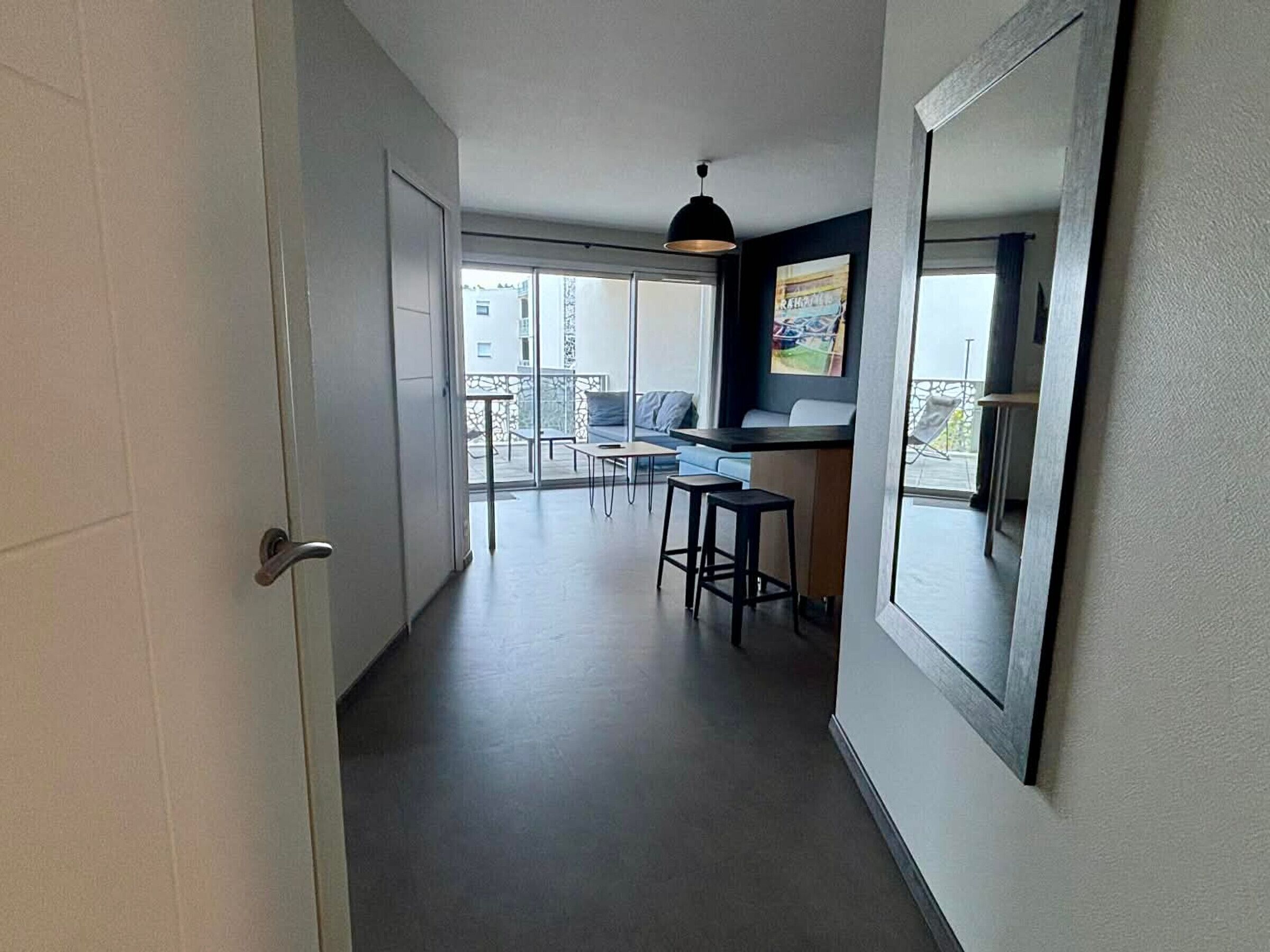 Un couloir étroit mène à un balcon qui comprend un coin repas, un bar et une grande fenêtre.
