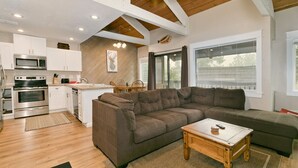 A modern kitchen with white cabinets, a large brown sectional sofa, and a wooden coffee table. - Mammoth Condo with Hot Tub (Mammoth Lakes)