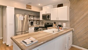 A modern kitchen with white cabinetry, stainless steel appliances, and a wooden countertop. - Mammoth Condo with Hot Tub (Mammoth Lakes)