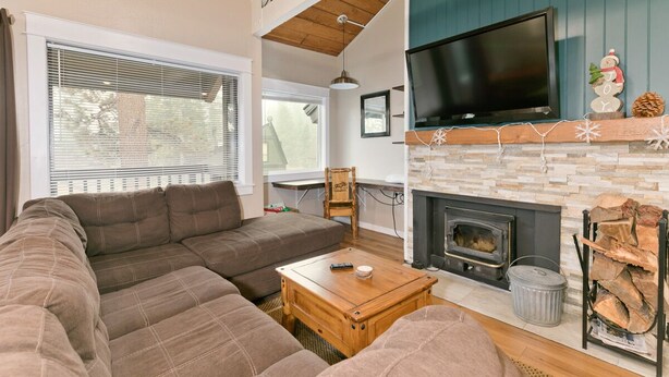 A cozy living room with a sectional sofa, a fireplace, and a TV mounted above it. - Mammoth Condo with Hot Tub (Mammoth Lakes)