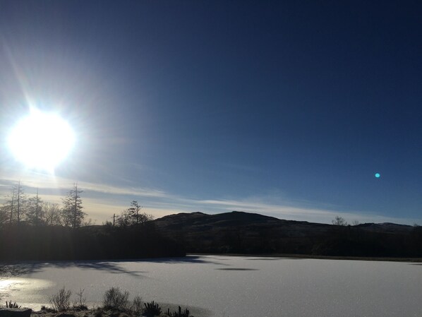 A frozen lake with a clear sky and distant mountains. - Cosy Woodland off Grid Shepherds Hut - Hazel (Castle Douglas)
