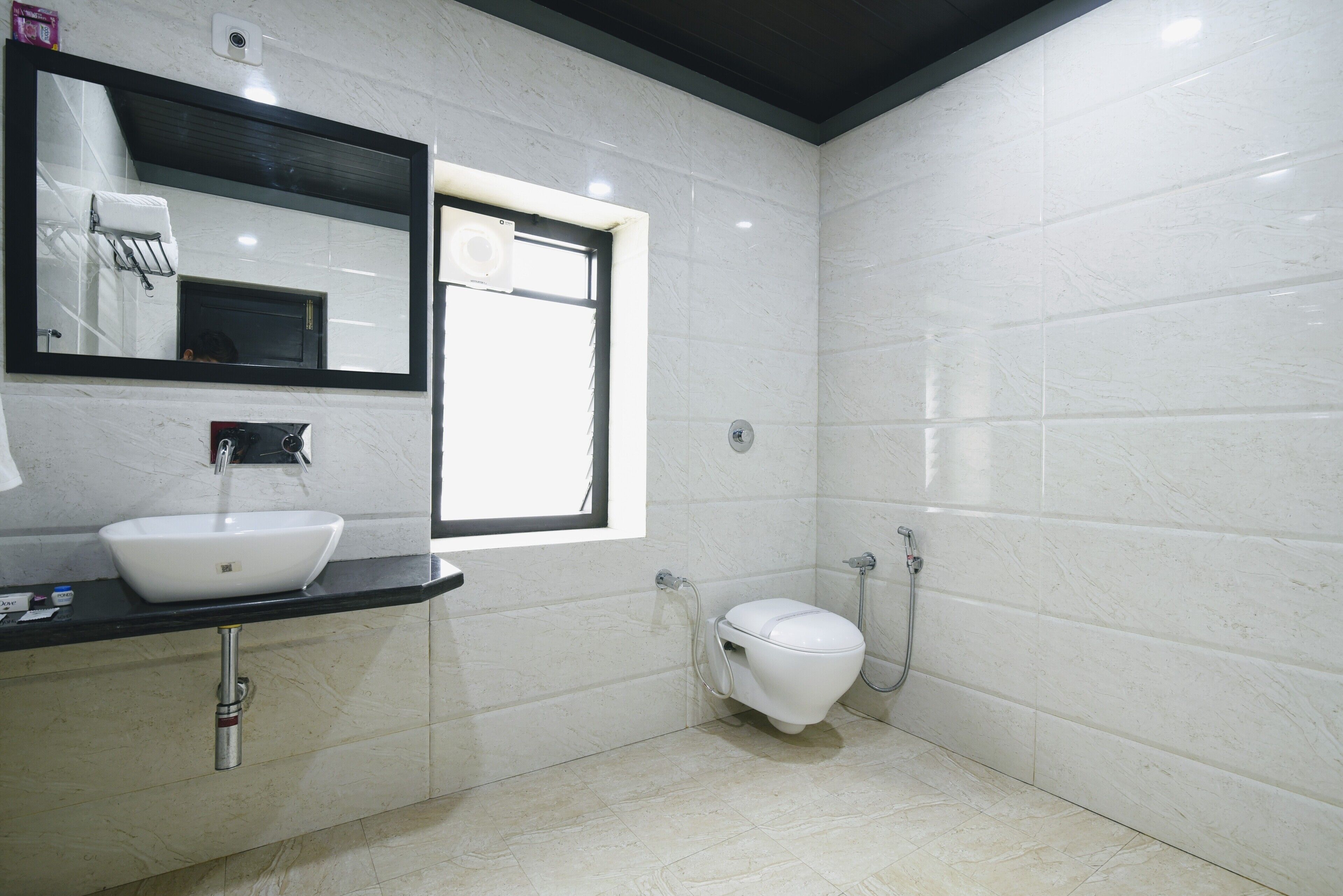 A modern bathroom with a white sink, a mirror, a toilet, and a shower.