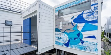 A modern building with a blue door and a large window with a blue abstract painting.