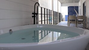 A spa area with a large bathtub, a glass-enclosed shower, and wicker chairs.